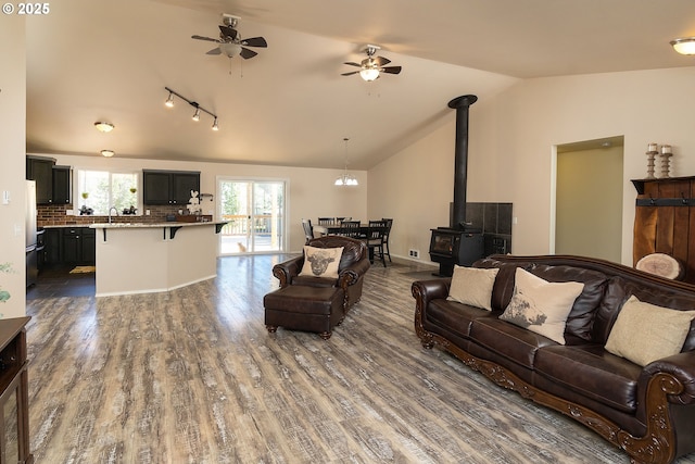 16050 Dick Rd, La Pine, OR 97739 - living room with vaulted ceiling, dark wood-style flooring, a wood stove, and a ceiling fan