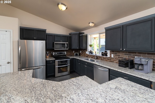 16050 Dick Rd, La Pine, OR 97739 - kitchen featuring appliances with stainless steel finishes, lofted ceiling, light stone counters, backsplash, and dark cabinetry