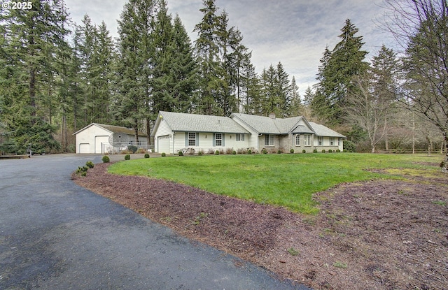 view of front of home with a detached garage, an outbuilding, and a front yard