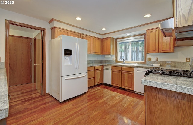 kitchen featuring light wood-style flooring, recessed lighting, white appliances, a sink, and tile counters