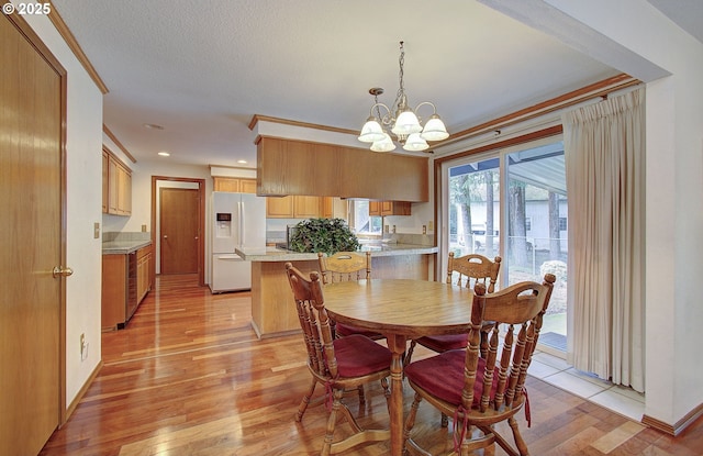 dining room featuring ornamental molding, light wood-type flooring, and an inviting chandelier