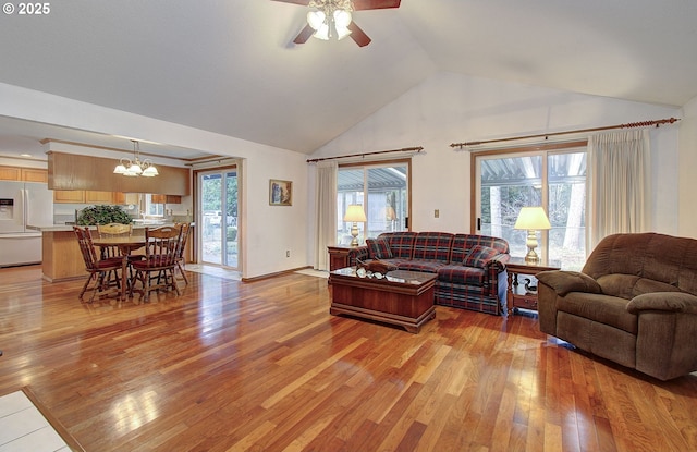 living area with ceiling fan with notable chandelier, high vaulted ceiling, a wealth of natural light, and light wood-style floors