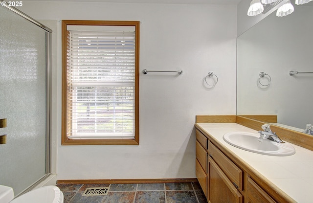 bathroom featuring toilet, vanity, visible vents, baseboards, and a shower with door