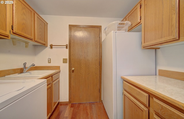 laundry area featuring washer / clothes dryer, light wood-type flooring, a sink, and cabinet space