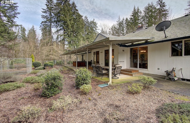 exterior space with roof with shingles, a patio, a chimney, and fence