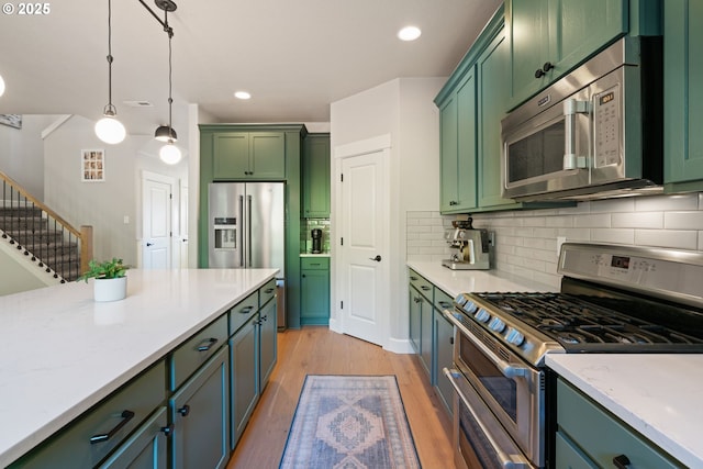 12721 Cottonwood Ave, Oregon City, OR 97045 - kitchen with stainless steel appliances, green cabinets, light wood finished floors, backsplash, and hanging light fixtures