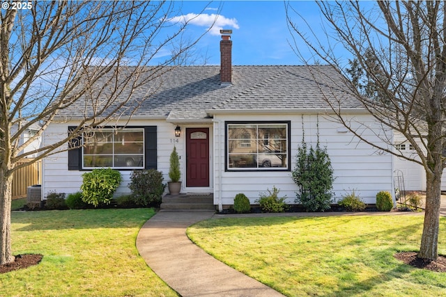 view of front of house featuring a front yard, roof with shingles, and a chimney