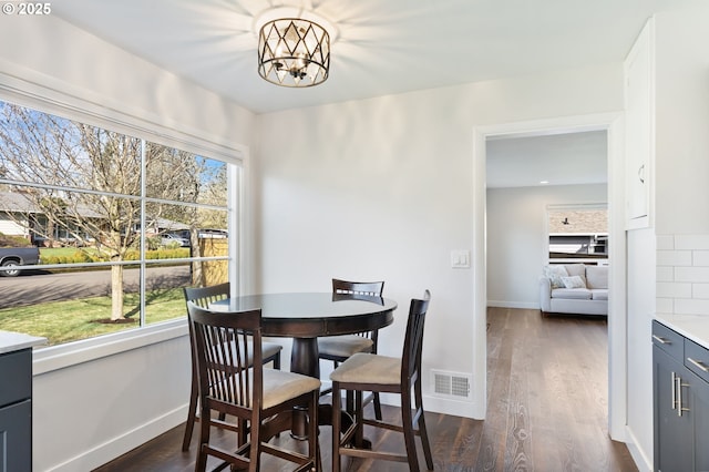 dining room featuring dark wood-style floors, plenty of natural light, and visible vents