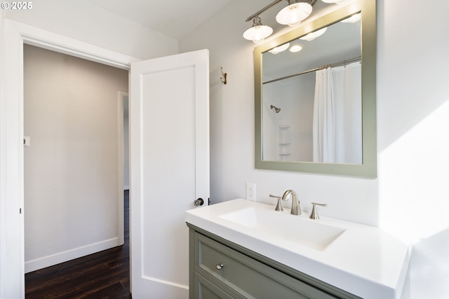 full bath with a shower with curtain, wood finished floors, vanity, and baseboards