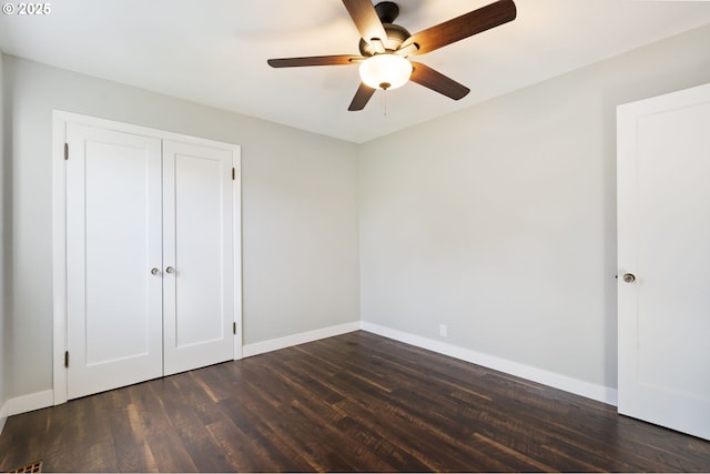 unfurnished bedroom with dark wood-style flooring, a closet, a ceiling fan, and baseboards