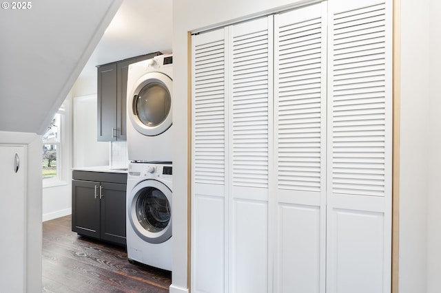 washroom featuring dark wood-style floors, stacked washer / dryer, and cabinet space