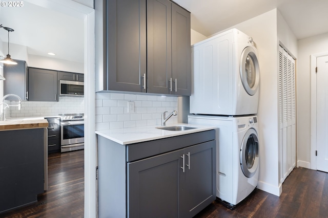 washroom with recessed lighting, laundry area, a sink, stacked washer / drying machine, and dark wood finished floors