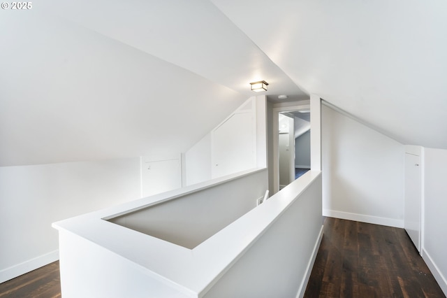 hall featuring lofted ceiling, dark wood-style flooring, an upstairs landing, and baseboards