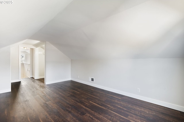 additional living space with baseboards, visible vents, and dark wood finished floors