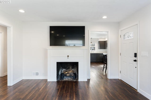 unfurnished living room with recessed lighting, a fireplace, dark wood finished floors, and baseboards