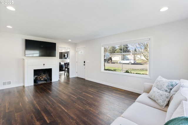 living room featuring recessed lighting, a fireplace, wood finished floors, visible vents, and baseboards