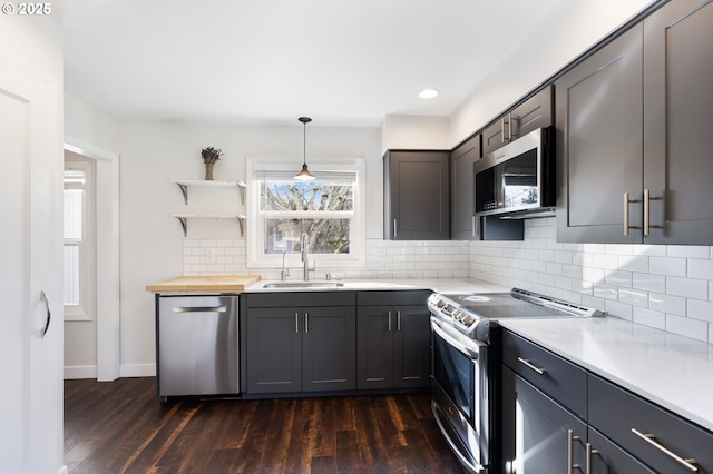 kitchen featuring dark wood-style floors, backsplash, stainless steel appliances, and a sink