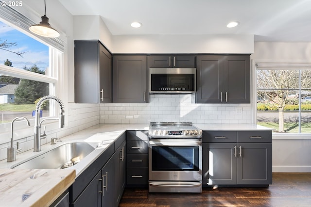 kitchen featuring appliances with stainless steel finishes, a healthy amount of sunlight, a sink, and decorative backsplash