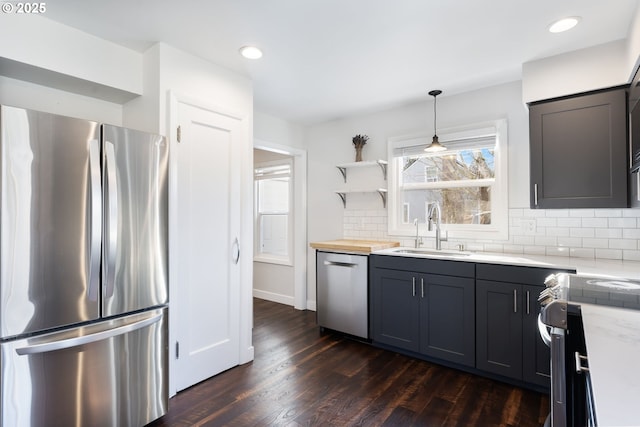 kitchen featuring dark wood-style floors, tasteful backsplash, recessed lighting, appliances with stainless steel finishes, and a sink