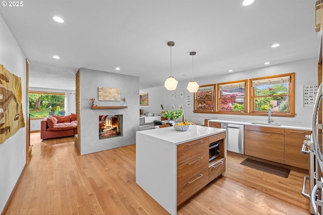 3905 NE Holman St, Portland, OR 97211 - kitchen featuring appliances with stainless steel finishes, a sink, modern cabinets, a multi sided fireplace, and a kitchen island