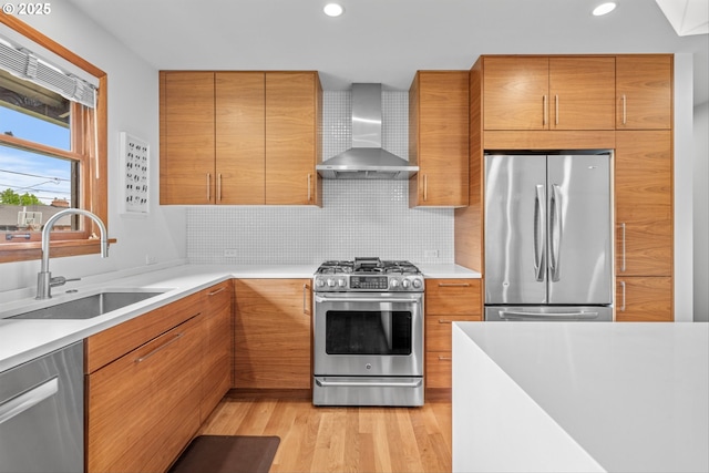 3905 NE Holman St, Portland, OR 97211 - kitchen with appliances with stainless steel finishes, wall chimney range hood, a sink, recessed lighting, and light wood-style flooring