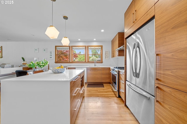 3905 NE Holman St, Portland, OR 97211 - kitchen with stainless steel appliances, light countertops, a sink, light wood-style floors, and brown cabinets