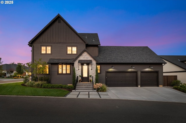 view of front of house with concrete driveway, roof with shingles, an attached garage, a front lawn, and board and batten siding