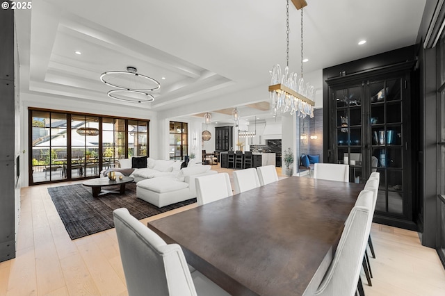 dining room featuring a tray ceiling, a chandelier, and light wood-type flooring