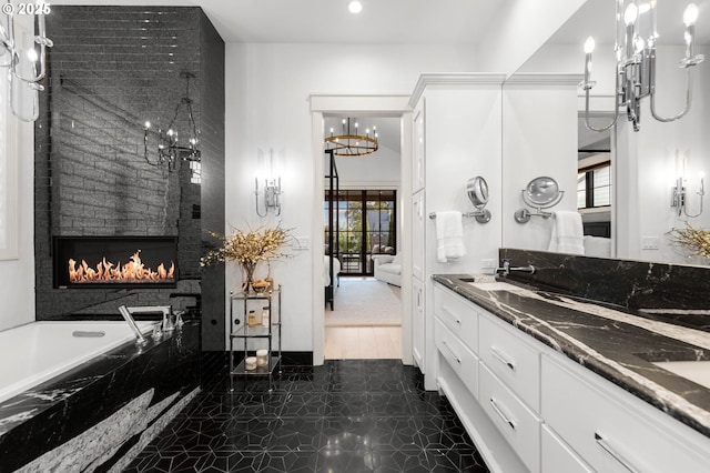 bathroom with a wealth of natural light, a large fireplace, vanity, and a relaxing tiled tub