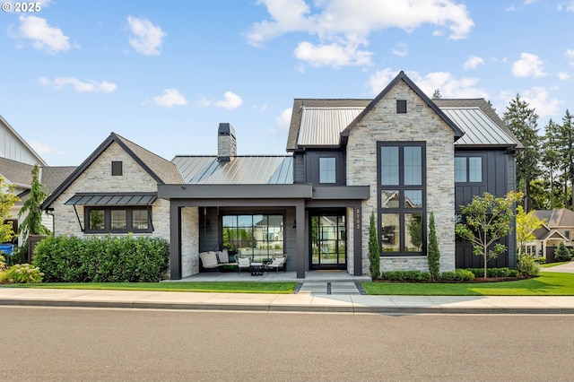 view of front of house featuring a chimney, board and batten siding, a standing seam roof, metal roof, and stone siding