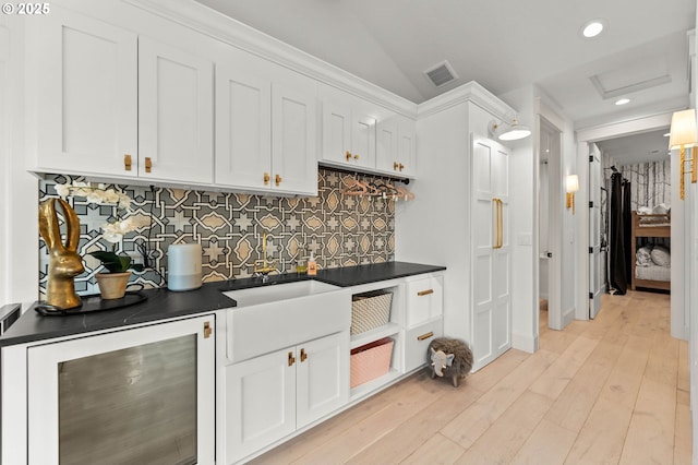 kitchen featuring wine cooler, tasteful backsplash, white cabinetry, and vaulted ceiling