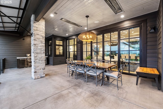 interior space featuring wooden ceiling, an inviting chandelier, decorative columns, concrete flooring, and wooden walls