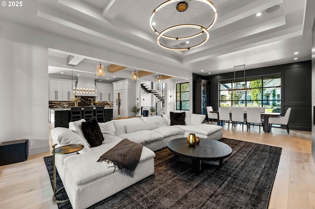 living area with a chandelier, a tray ceiling, and stairway