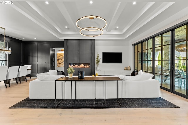 living room with a tray ceiling, a chandelier, french doors, and light hardwood / wood-style floors