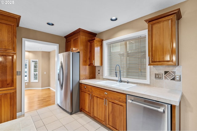kitchen with a sink, brown cabinetry, and stainless steel appliances