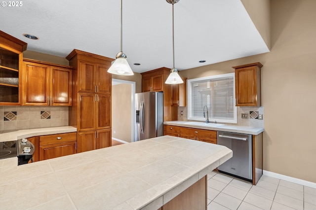 kitchen featuring baseboards, a sink, decorative backsplash, and appliances with stainless steel finishes