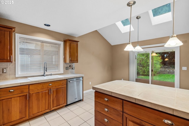 kitchen with hanging light fixtures, tasteful backsplash, brown cabinets, dishwasher, and a sink
