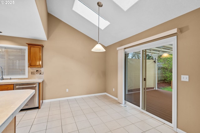 kitchen featuring brown cabinetry, a skylight, dishwasher, light countertops, and a sink