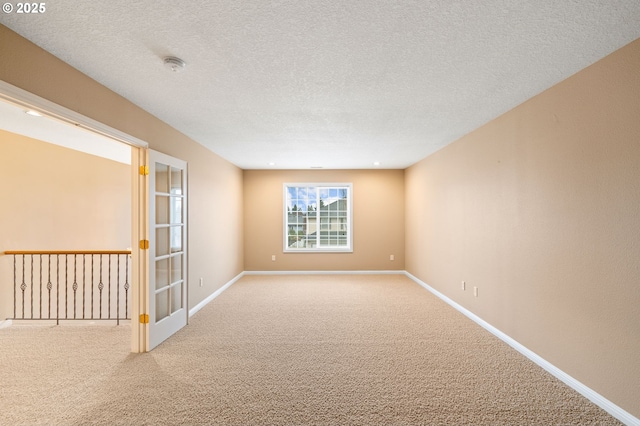 carpeted spare room with baseboards and a textured ceiling