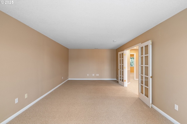 unfurnished room with baseboards, light carpet, and french doors
