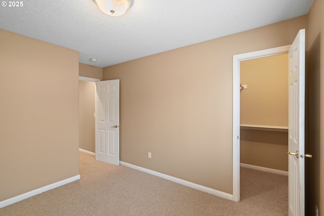 unfurnished bedroom featuring carpet floors, baseboards, and a spacious closet