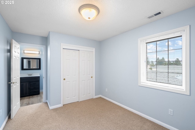 unfurnished bedroom with a closet, baseboards, light colored carpet, and visible vents