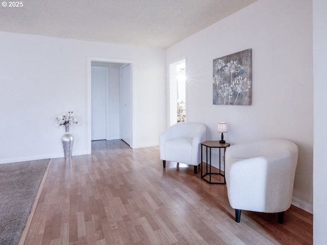 sitting room featuring a textured ceiling, wood finished floors, and baseboards