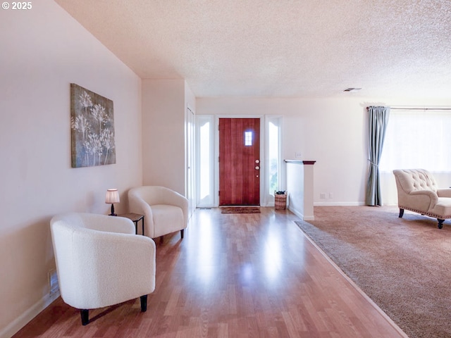 entryway with a textured ceiling, wood finished floors, and baseboards