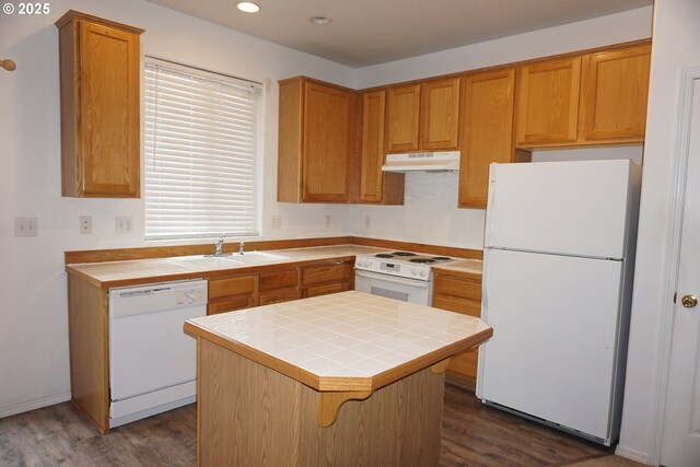 kitchen featuring a kitchen island, a sink, tile counters, under cabinet range hood, and white appliances