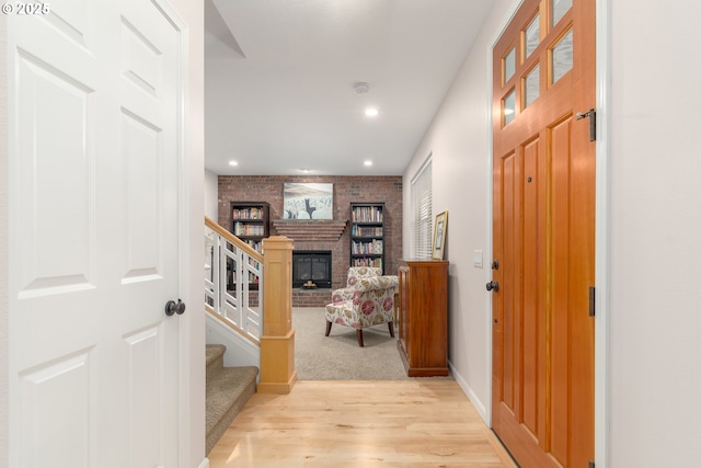 hallway featuring brick wall and light hardwood / wood-style floors