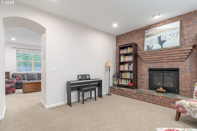 living room featuring a brick fireplace and carpet