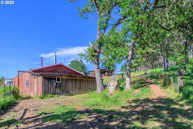 view of yard featuring a pole building, an outdoor structure, and fence