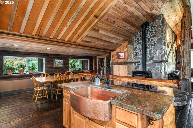 kitchen featuring a sink, lofted ceiling, a wood stove, dark wood-type flooring, and wood ceiling