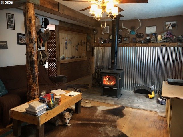 living room with hardwood / wood-style flooring, a wood stove, and ceiling fan